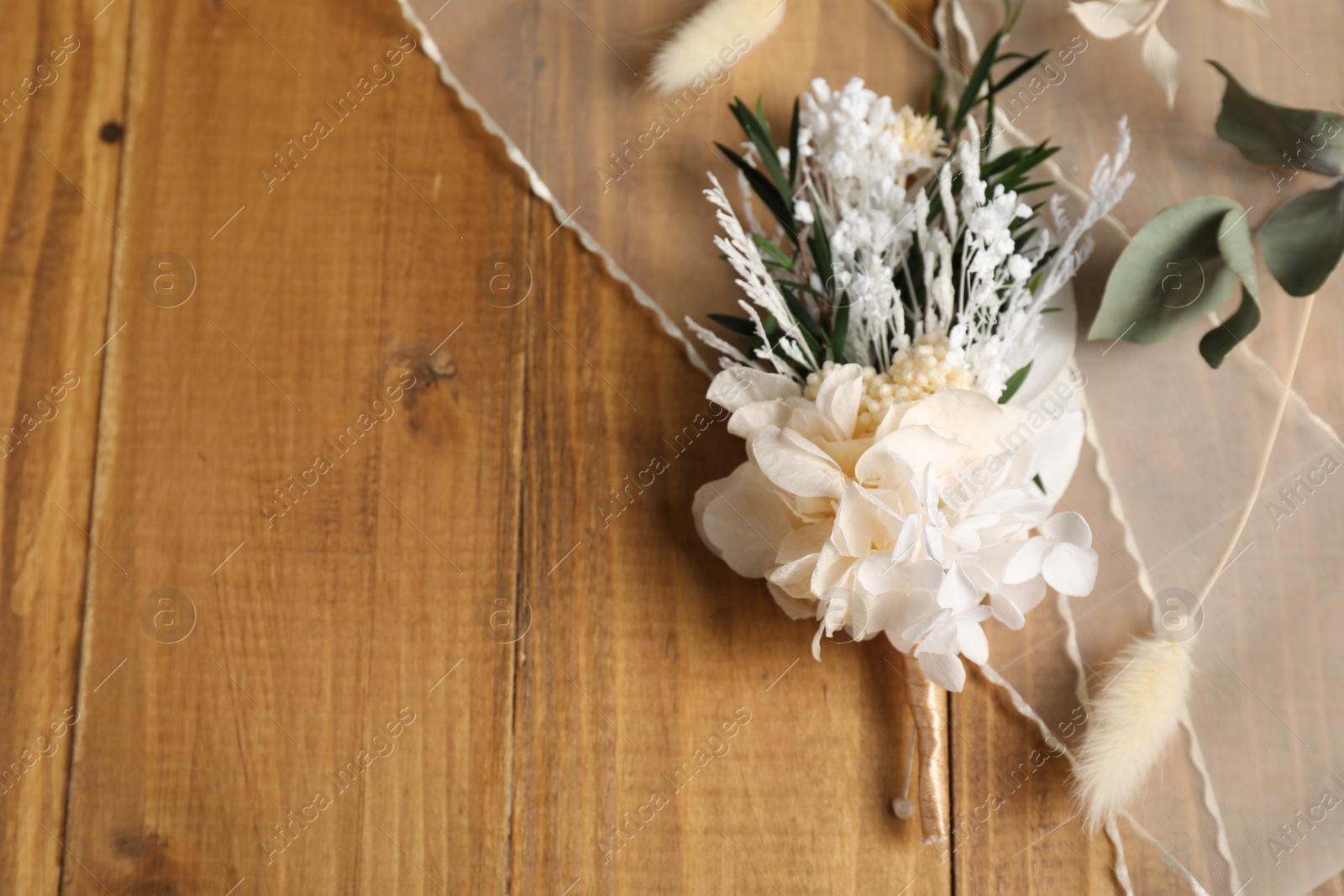 Photo of Stylish boutonniere and ribbon on wooden table, top view. Space for text