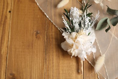 Photo of Stylish boutonniere and ribbon on wooden table, top view. Space for text