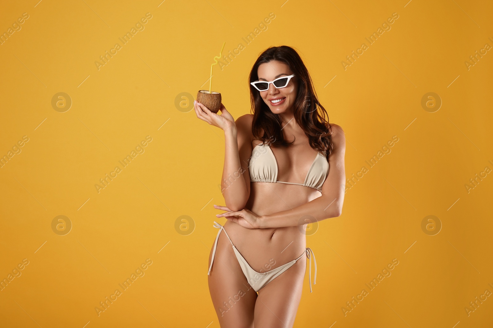 Photo of Beautiful woman in stylish bikini with tropical cocktail on yellow background