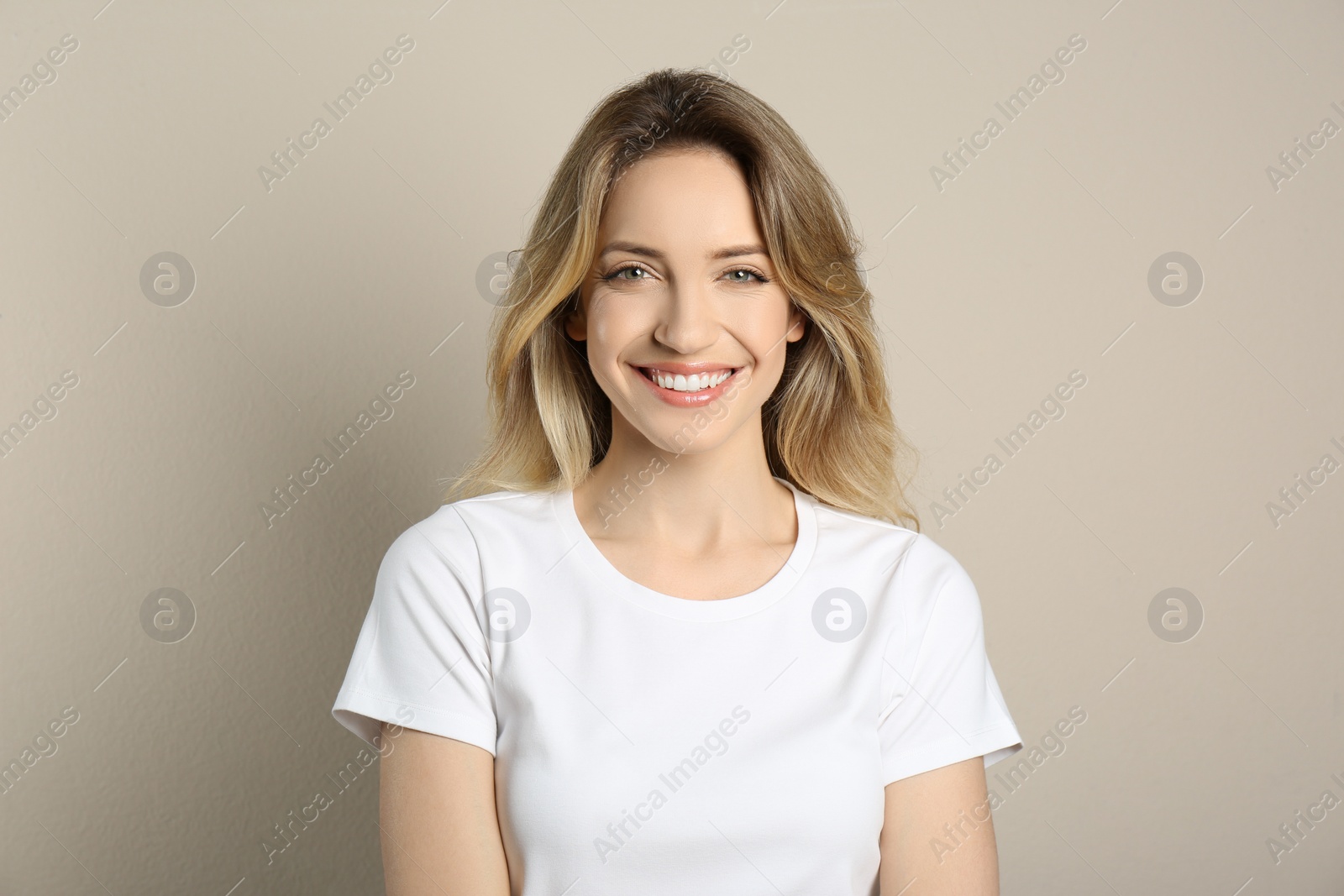 Photo of Portrait of happy young woman with beautiful blonde hair and charming smile on beige background