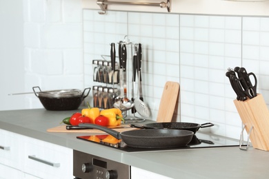 Photo of Clean frying pans and holder with knives in kitchen