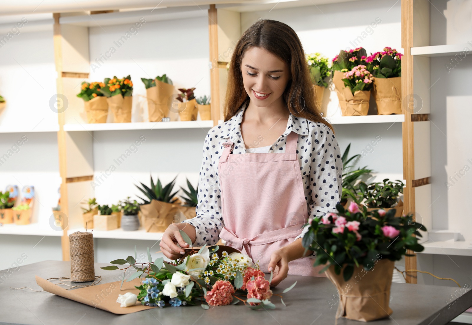 Photo of Florist making bouquet with fresh flowers at table in shop