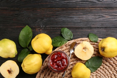 Delicious quince jam and fruits on black wooden table, flat lay. Space for text