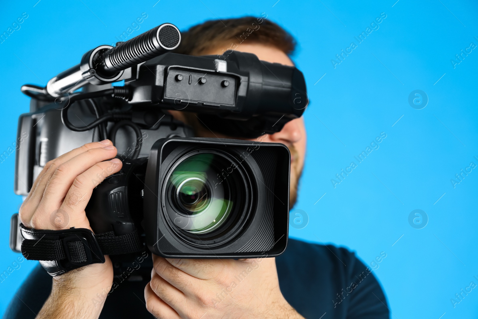 Photo of Operator with professional video camera on blue background