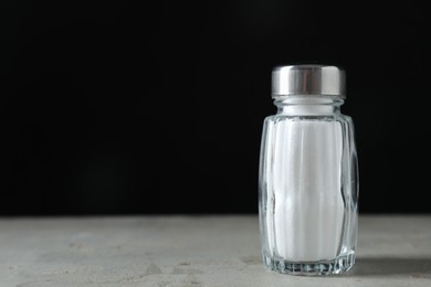 Photo of Salt shaker on light table against black background. Space for text