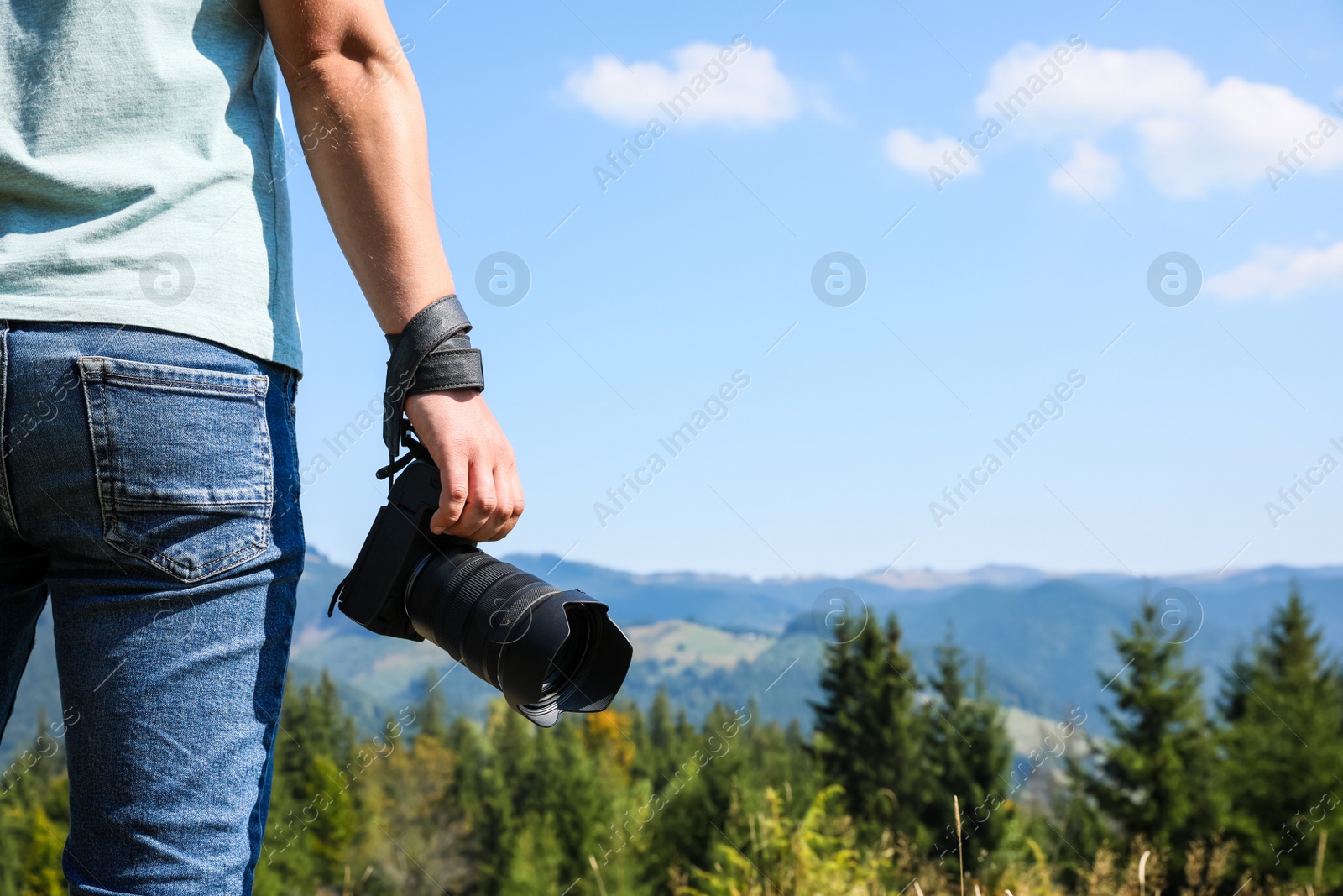 Photo of Professional photographer with modern camera in mountains, closeup. Space for text