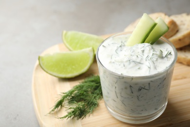 Photo of Glass bowl of Tzatziki cucumber sauce on wooden board, space for text