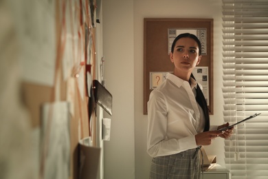 Detective looking at evidence board in office