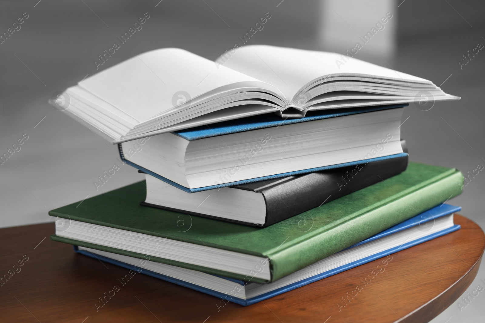 Photo of Stack of hardcover books on wooden coffee table indoors, closeup