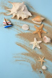Flat lay composition with beautiful sea stars and sand on light blue background
