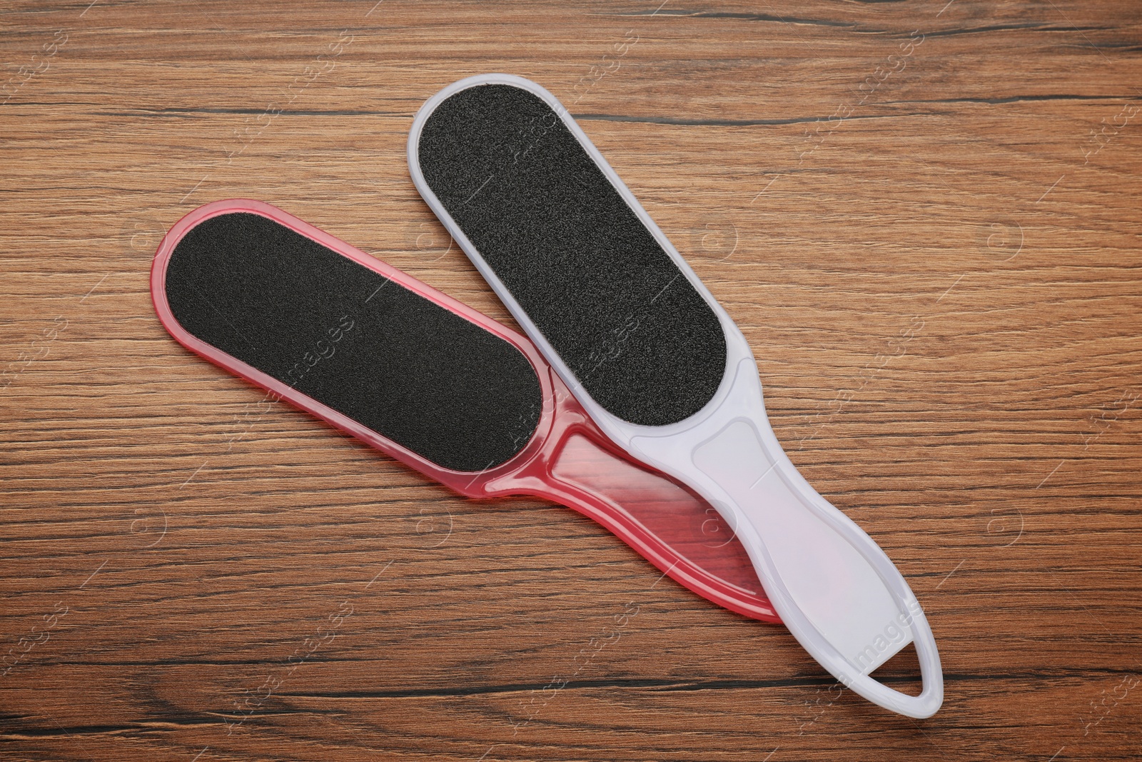Photo of Colorful foot files on wooden table, flat lay. Pedicure tools