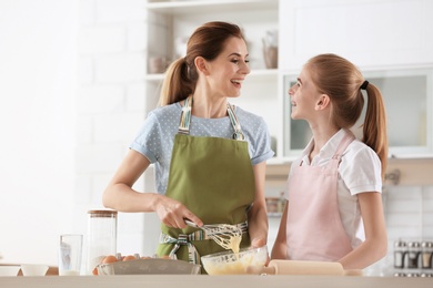 Mother and her daughter making dough at table in kitchen