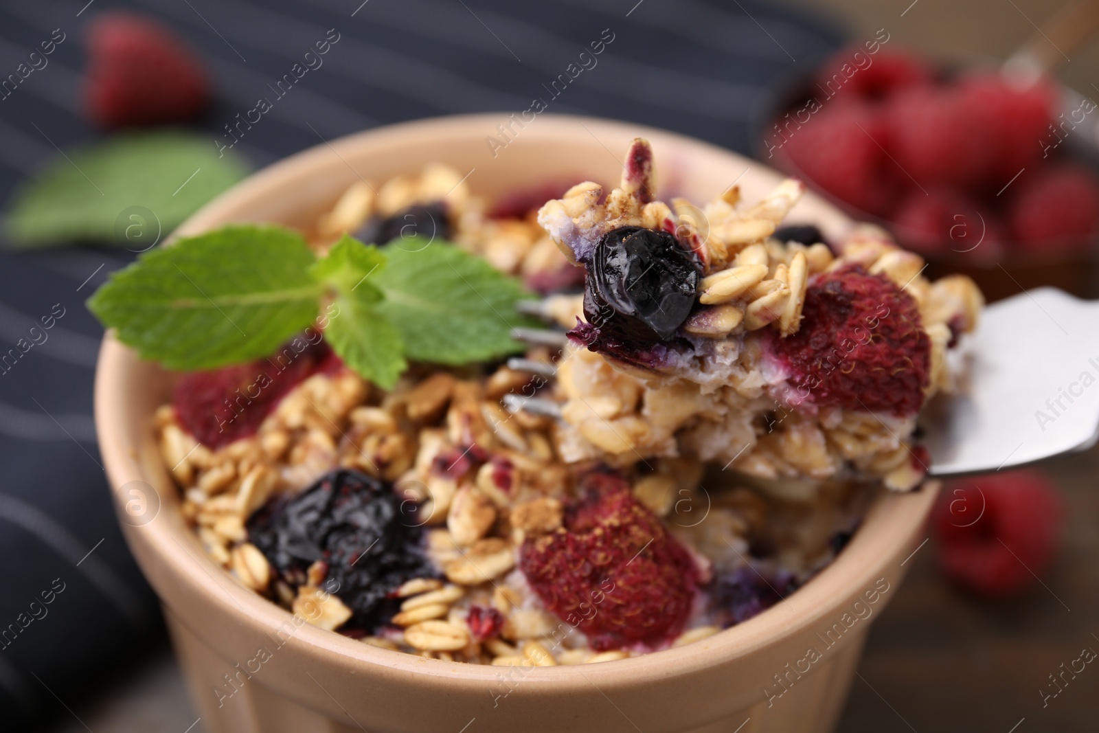 Photo of Eating tasty baked oatmeal with berries at table, closeup