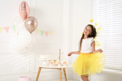 Photo of Cute little girl wearing fairy costume with wings in decorated room. Space for text