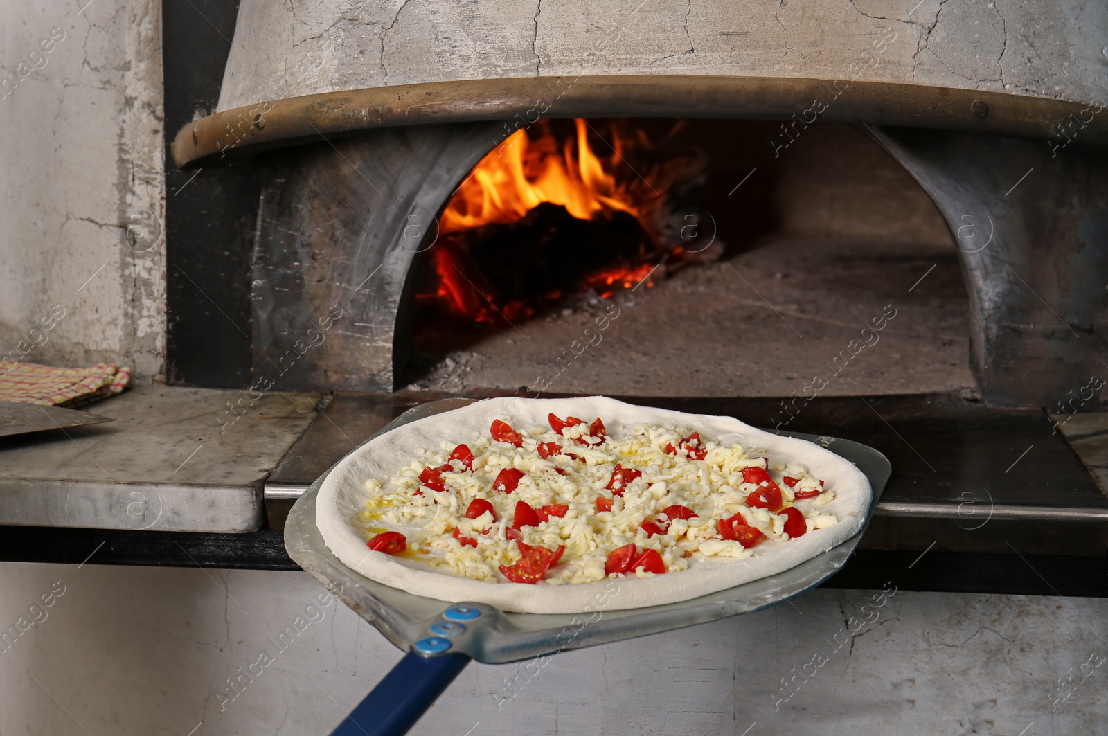 Photo of Putting tasty pizza into oven in  restaurant kitchen