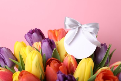 Photo of Bouquet of beautiful colorful tulips with blank card on pink background, closeup. Birthday celebration