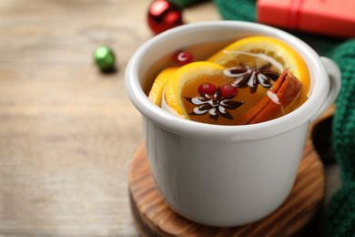 Photo of Aromatic mulled wine on wooden board, closeup