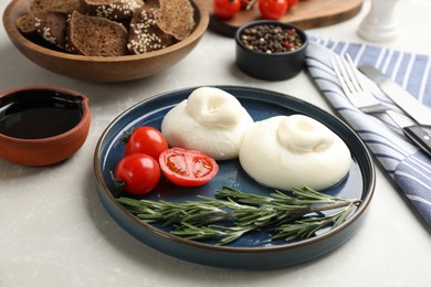 Photo of Delicious burrata cheese with rosemary and tomatoes served on light table