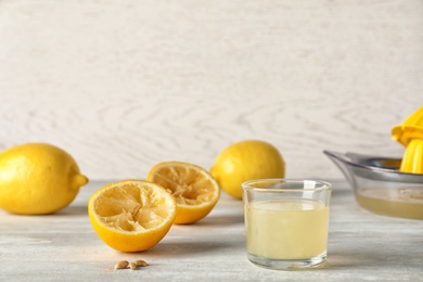 Photo of Composition with glass of juice and squeezed  lemons on table