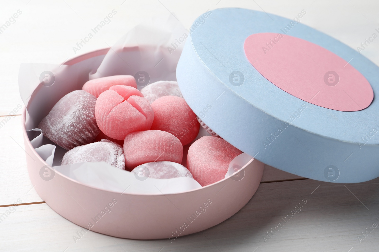 Photo of Many different delicious mochi in box on white wooden table. Traditional Japanese dessert