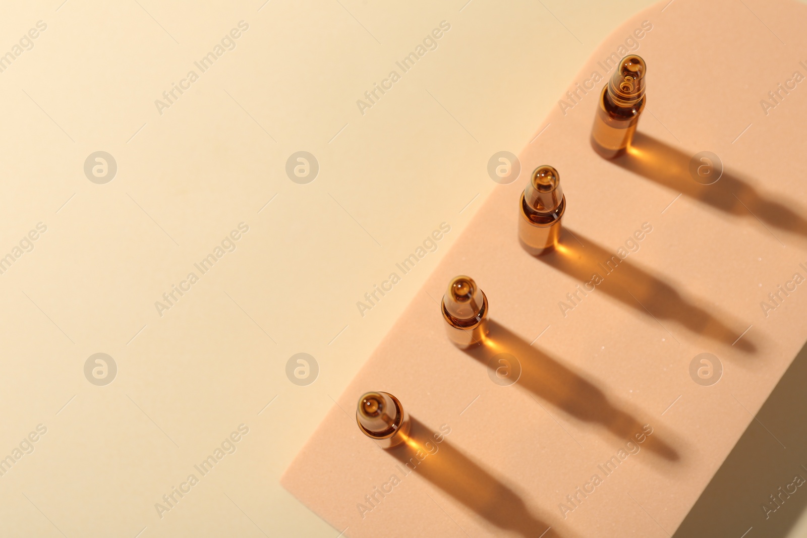 Photo of Glass ampoules with liquid on beige background, top view. Space for text