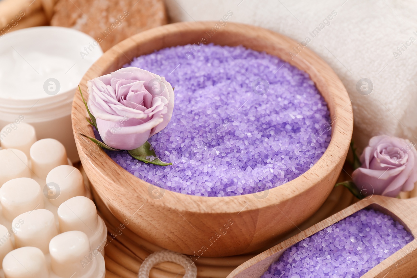 Photo of Sea salt, jar of cream and beautiful roses on wicker mat, closeup