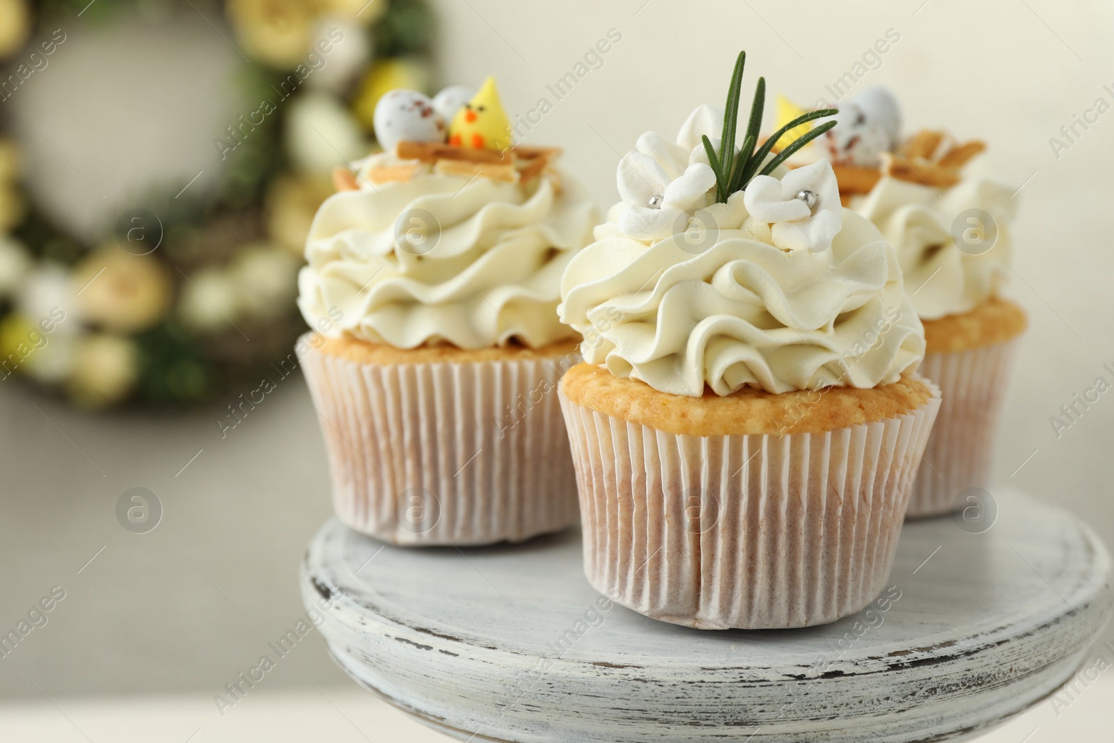 Photo of Tasty Easter cupcakes with vanilla cream on dessert stand, closeup