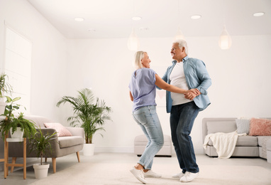 Happy mature couple dancing together in living room