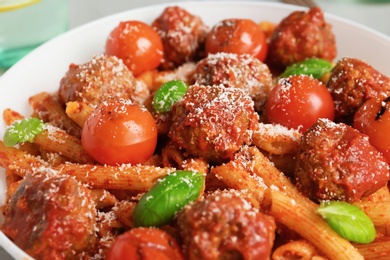 Delicious pasta with meatballs and tomato sauce on plate, closeup