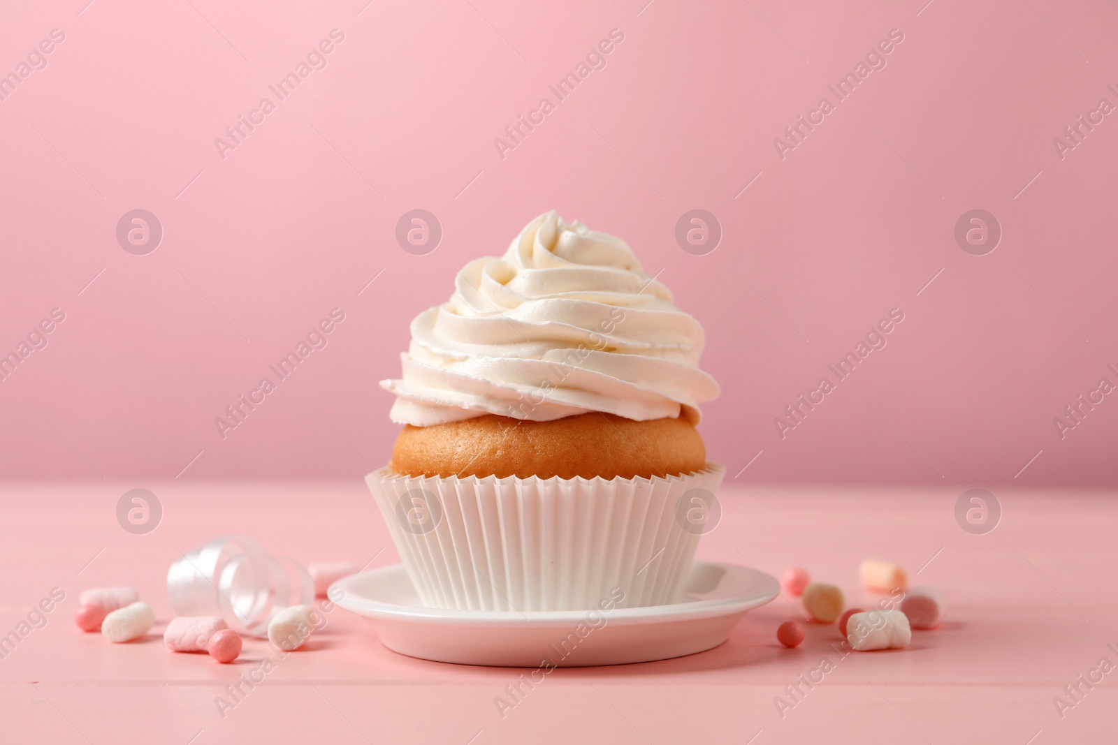 Photo of Delicious cupcake decorated with cream on pink wooden table