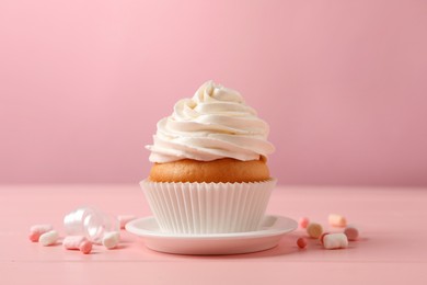 Photo of Delicious cupcake decorated with cream on pink wooden table