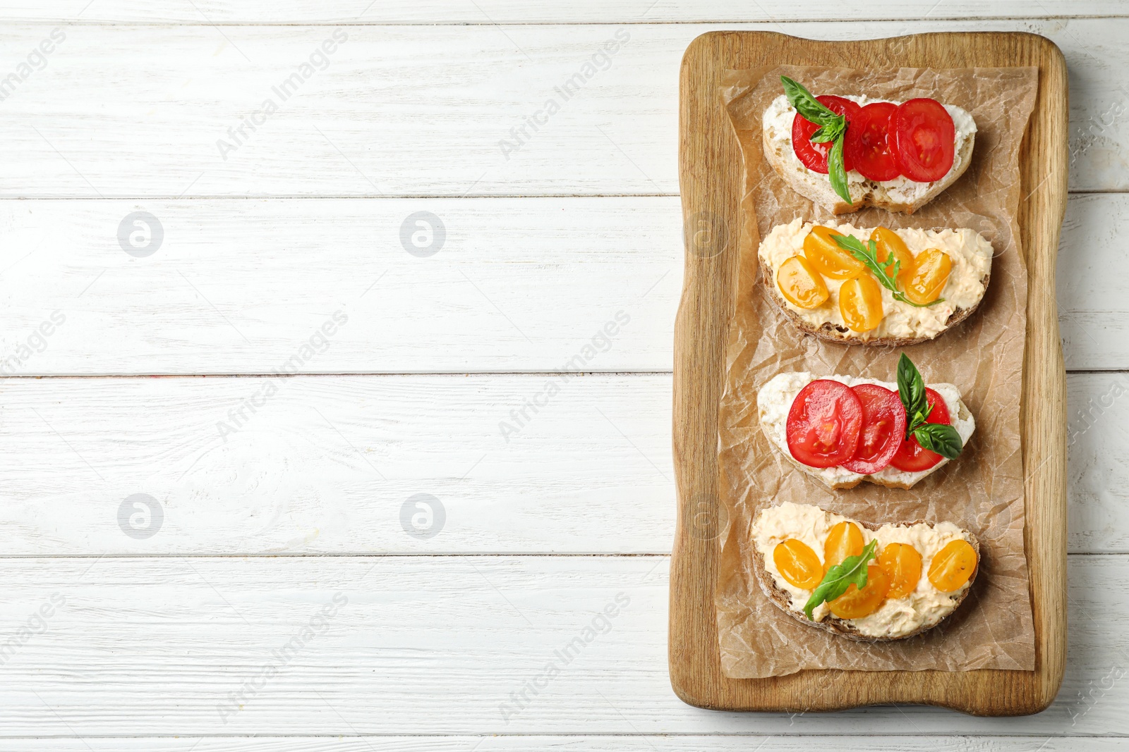 Photo of Tasty fresh tomato bruschettas on white wooden table, flat lay. Space for text