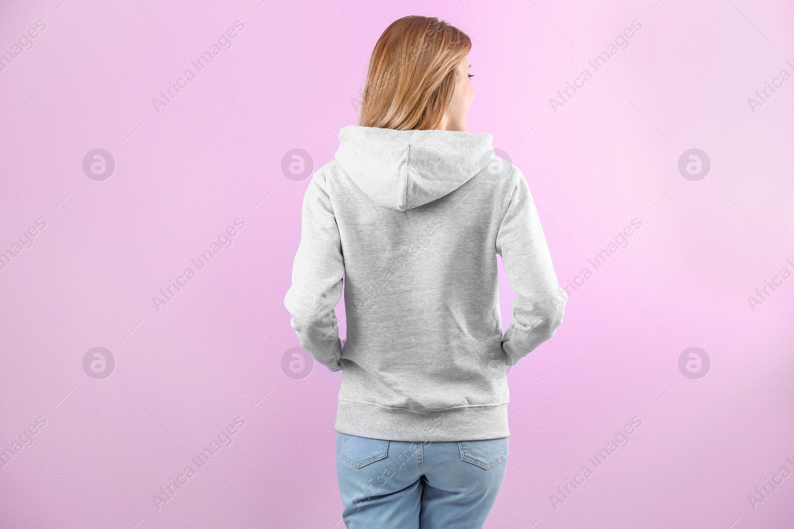 Photo of Woman in hoodie sweater on color background. Space for design