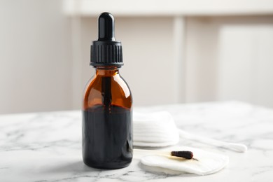 Photo of Bottle of medical iodine, cotton pads and buds on white marble table. Space for text