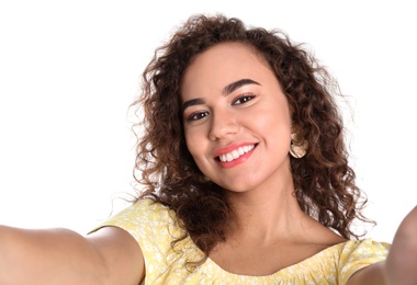 Beautiful laughing African-American woman taking selfie on white background