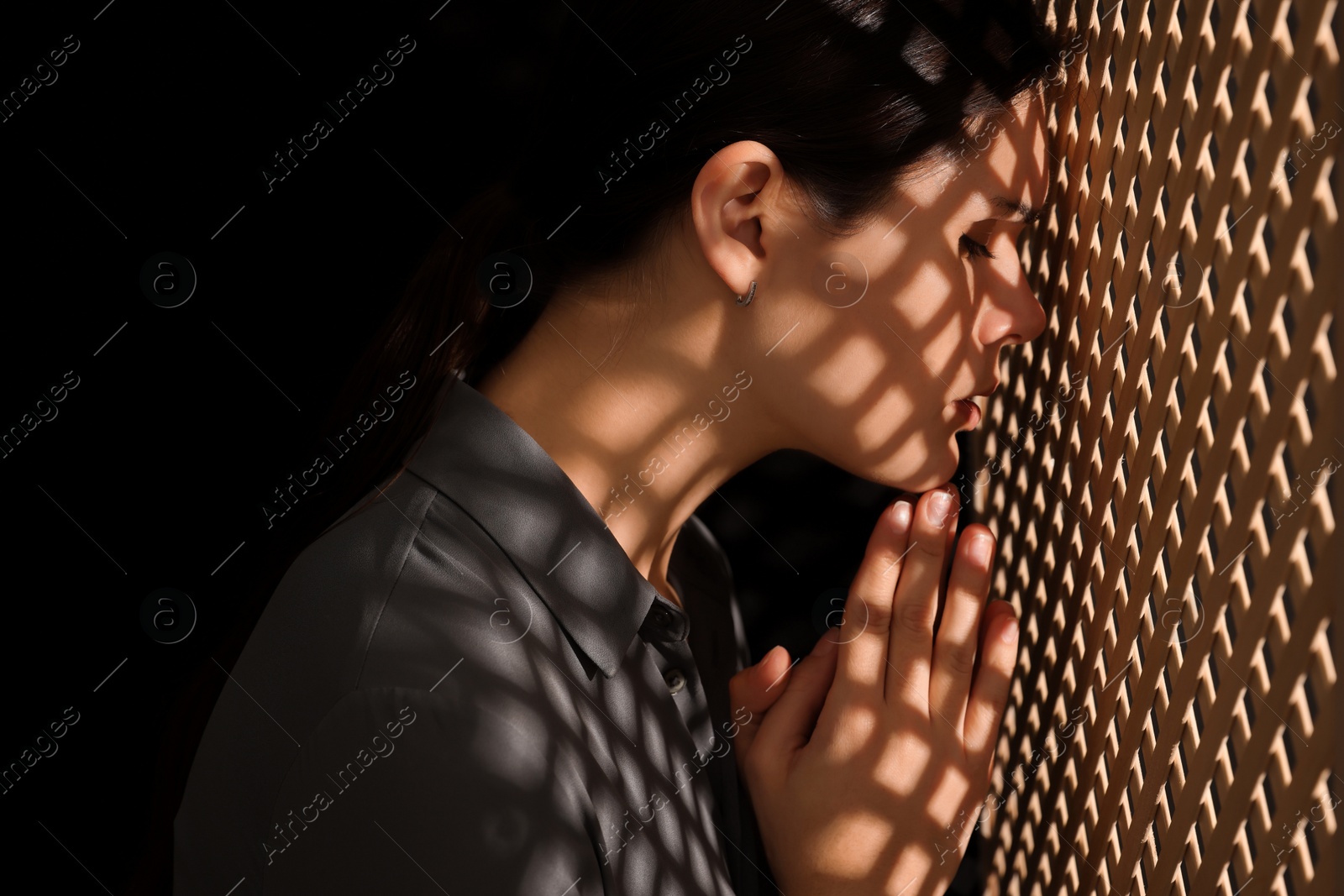 Photo of Woman praying to God during confession in booth