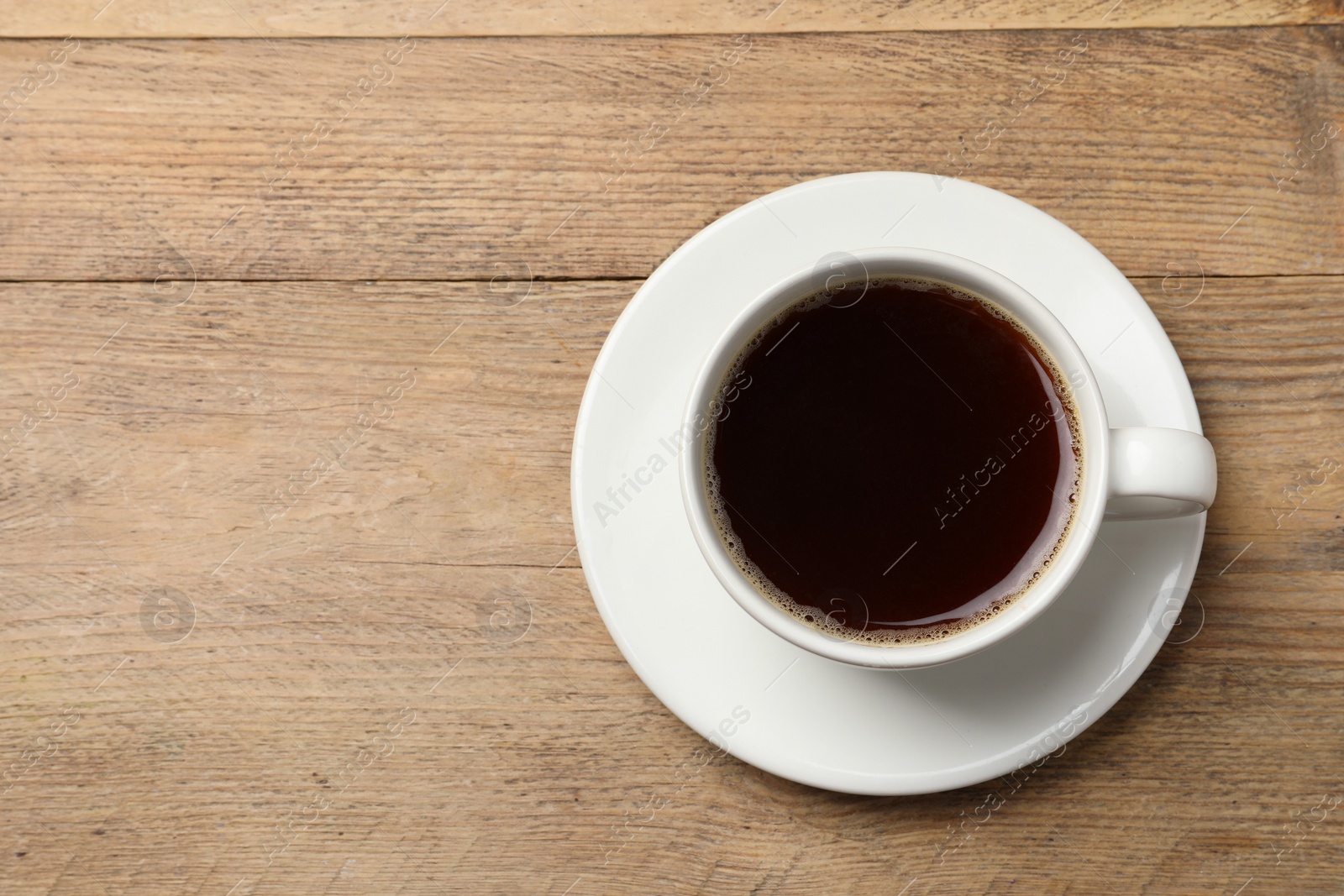 Photo of Cup of aromatic coffee on wooden table, top view. Space for text