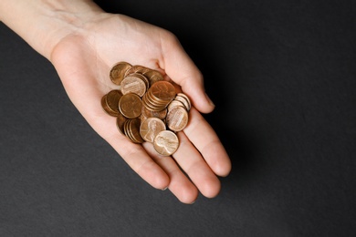 Young woman holding coins on black background, top view