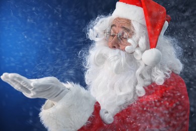 Photo of Merry Christmas. Santa Claus blowing snow on dark blue background