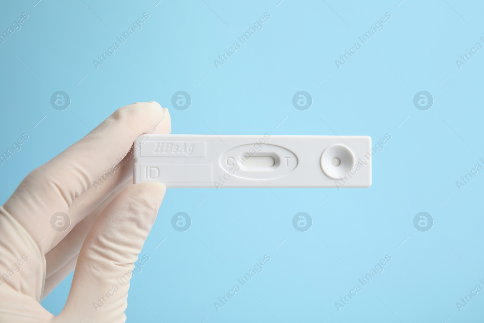 Photo of Doctor holding disposable express test for hepatitis on light blue background, closeup