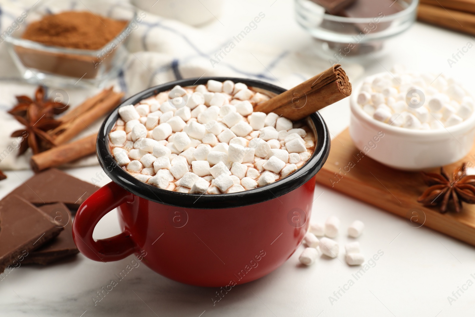 Photo of Tasty hot chocolate with marshmallows and ingredients on white marble table, closeup