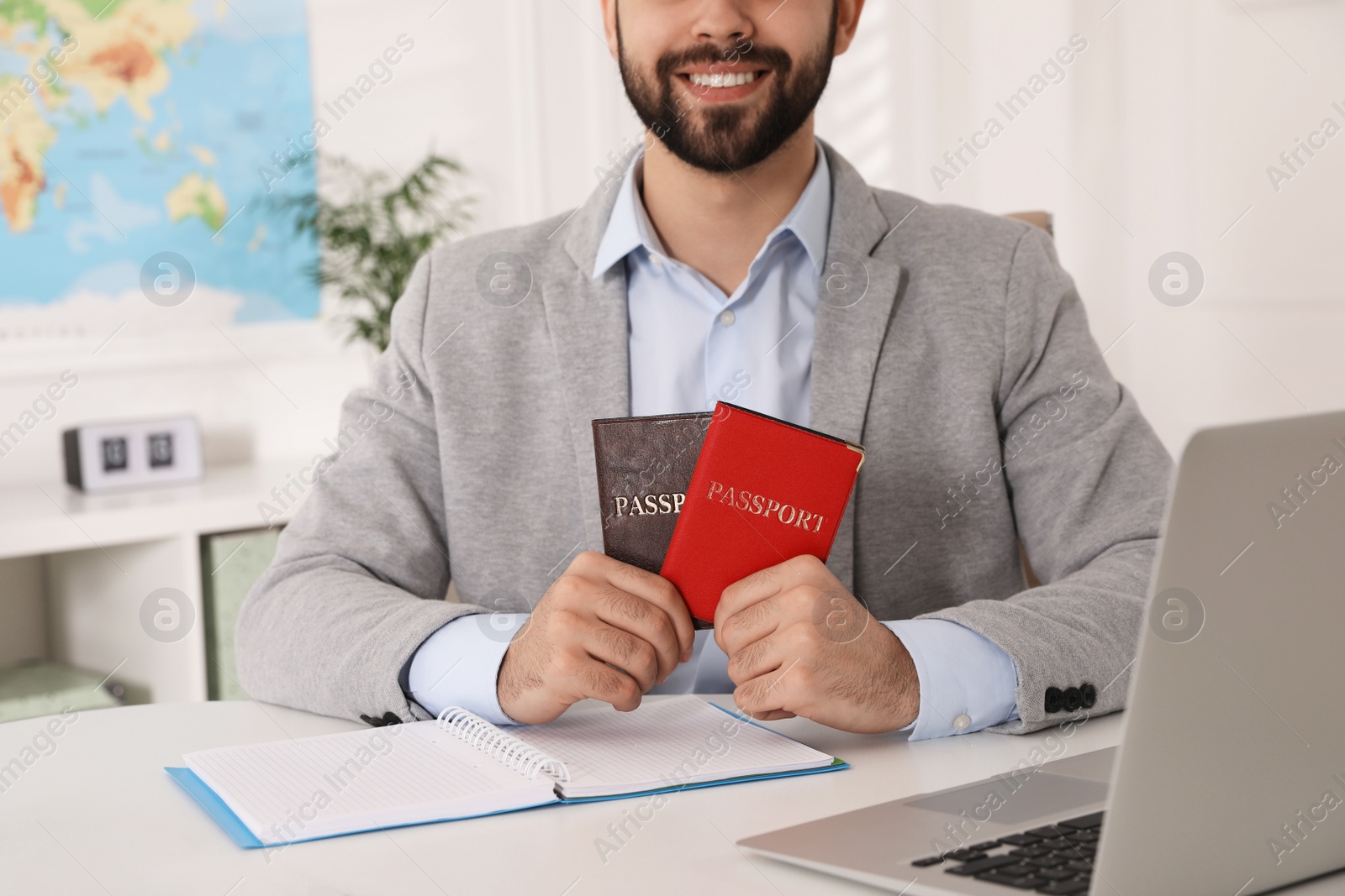 Photo of Happy manager holding passports at desk in travel agency, closeup