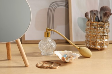 Photo of Mirror, jewelry and perfume on wooden dressing table