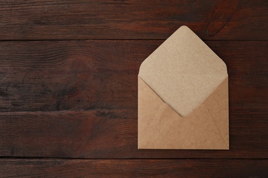 Photo of Brown paper envelope on wooden table, top view. Space for text