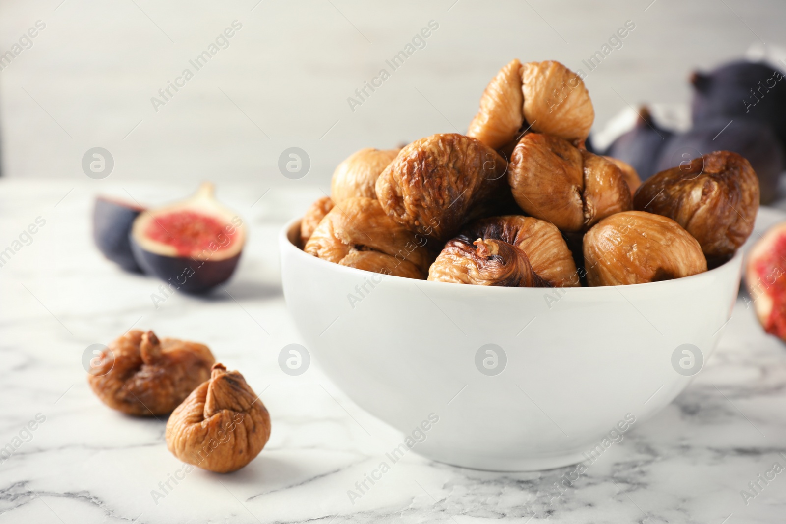 Photo of Bowl with delicious dried figs on marble table. Organic snack