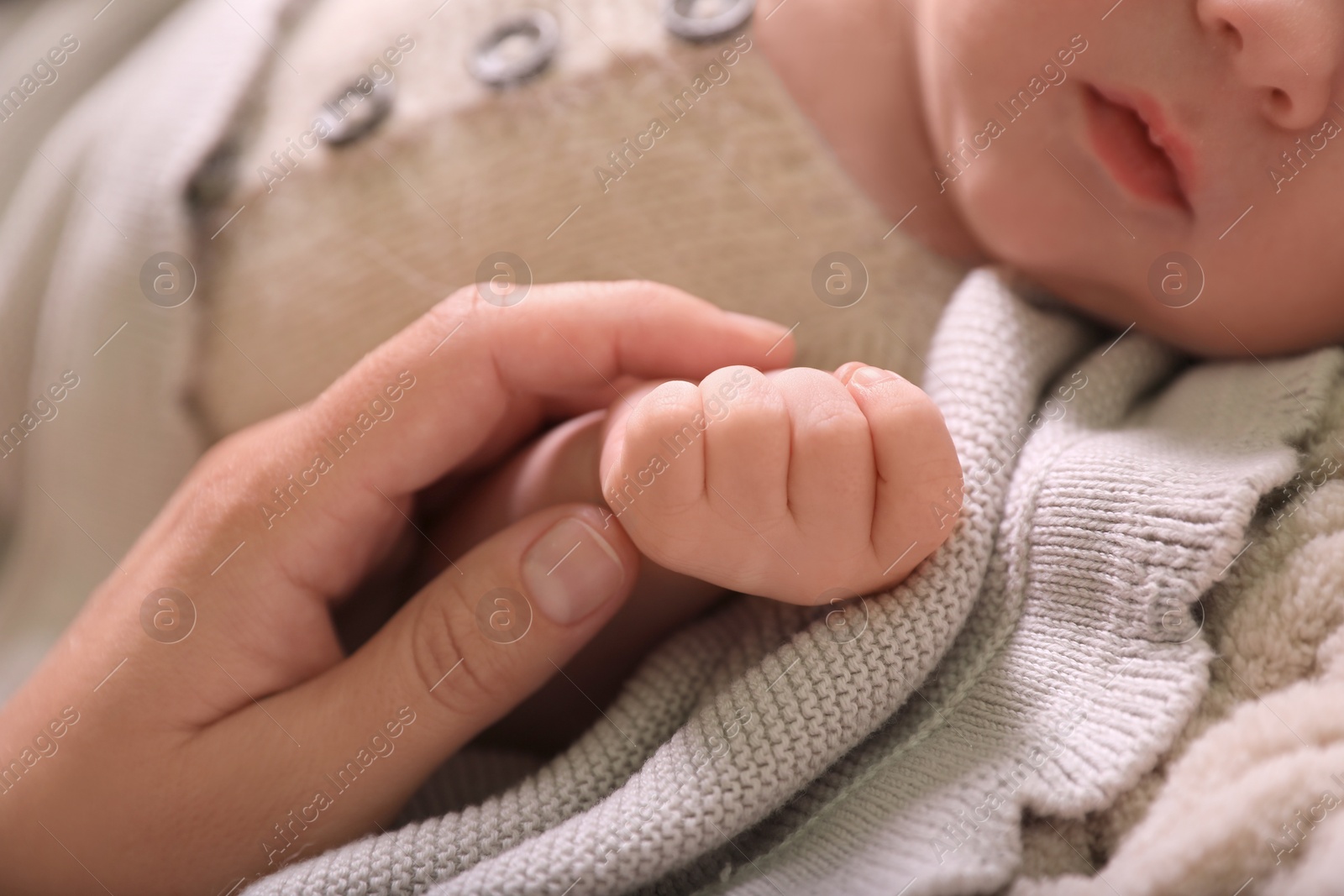 Photo of Mother and her newborn baby on beige crocheted plaid, closeup