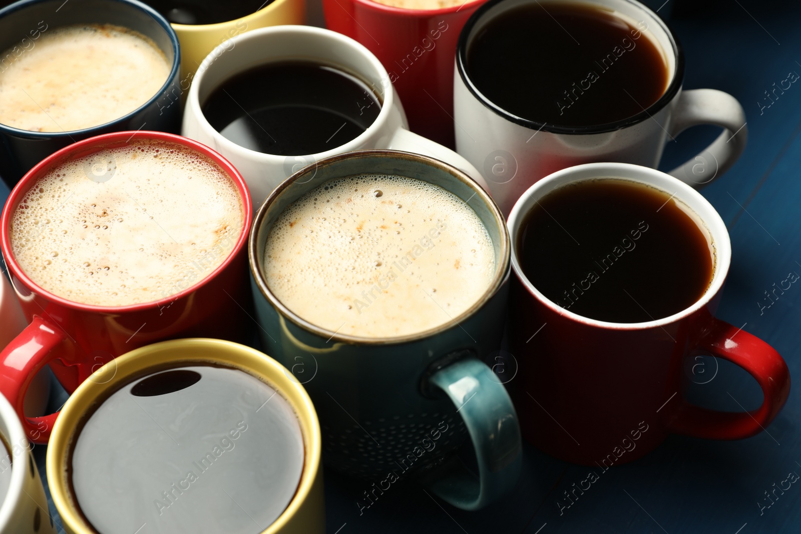 Photo of Many cups of different coffee drinks on blue table