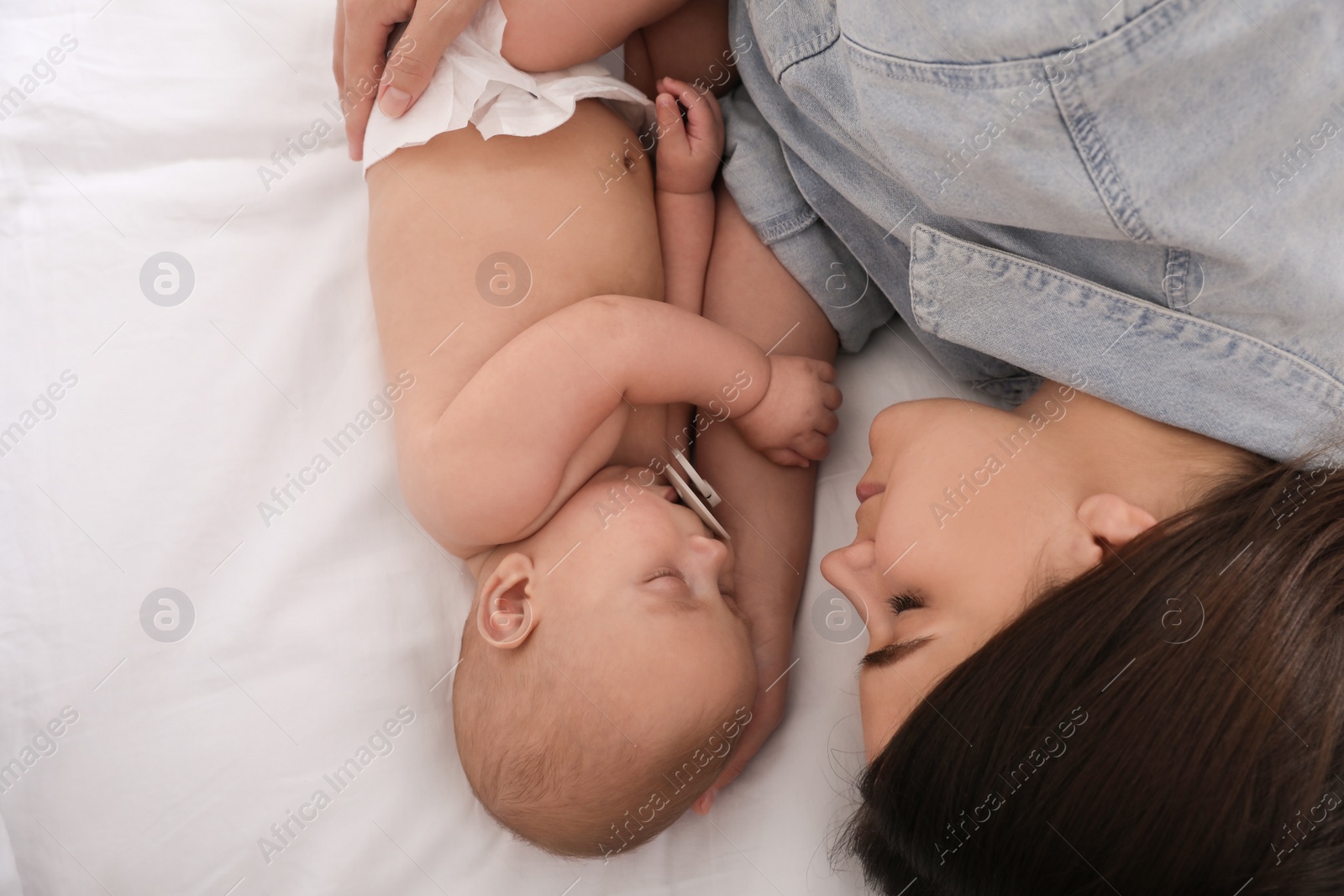 Photo of Mother with her cute baby sleeping on bed, top view