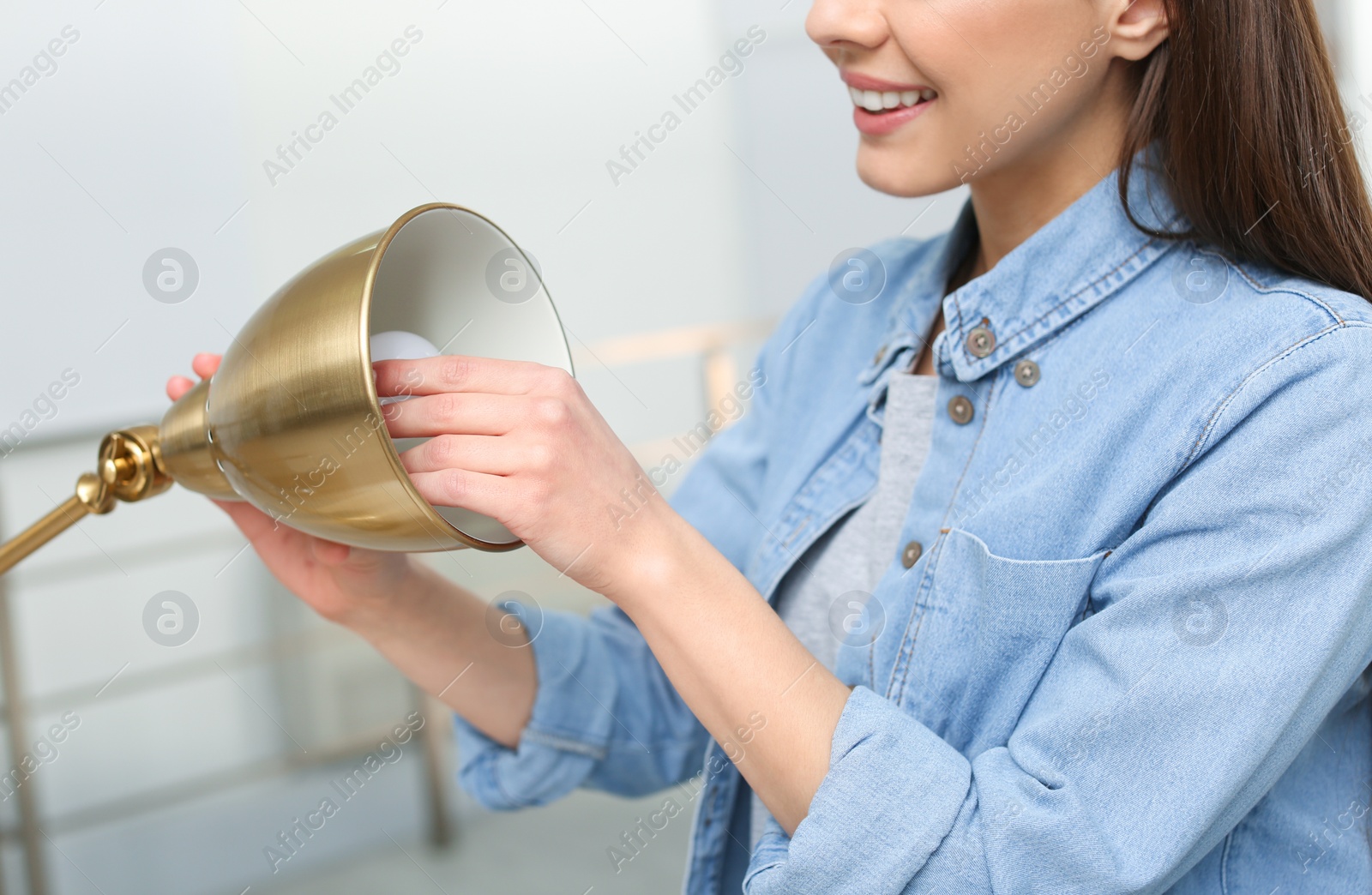 Photo of Woman changing light bulb in lamp indoors, closeup