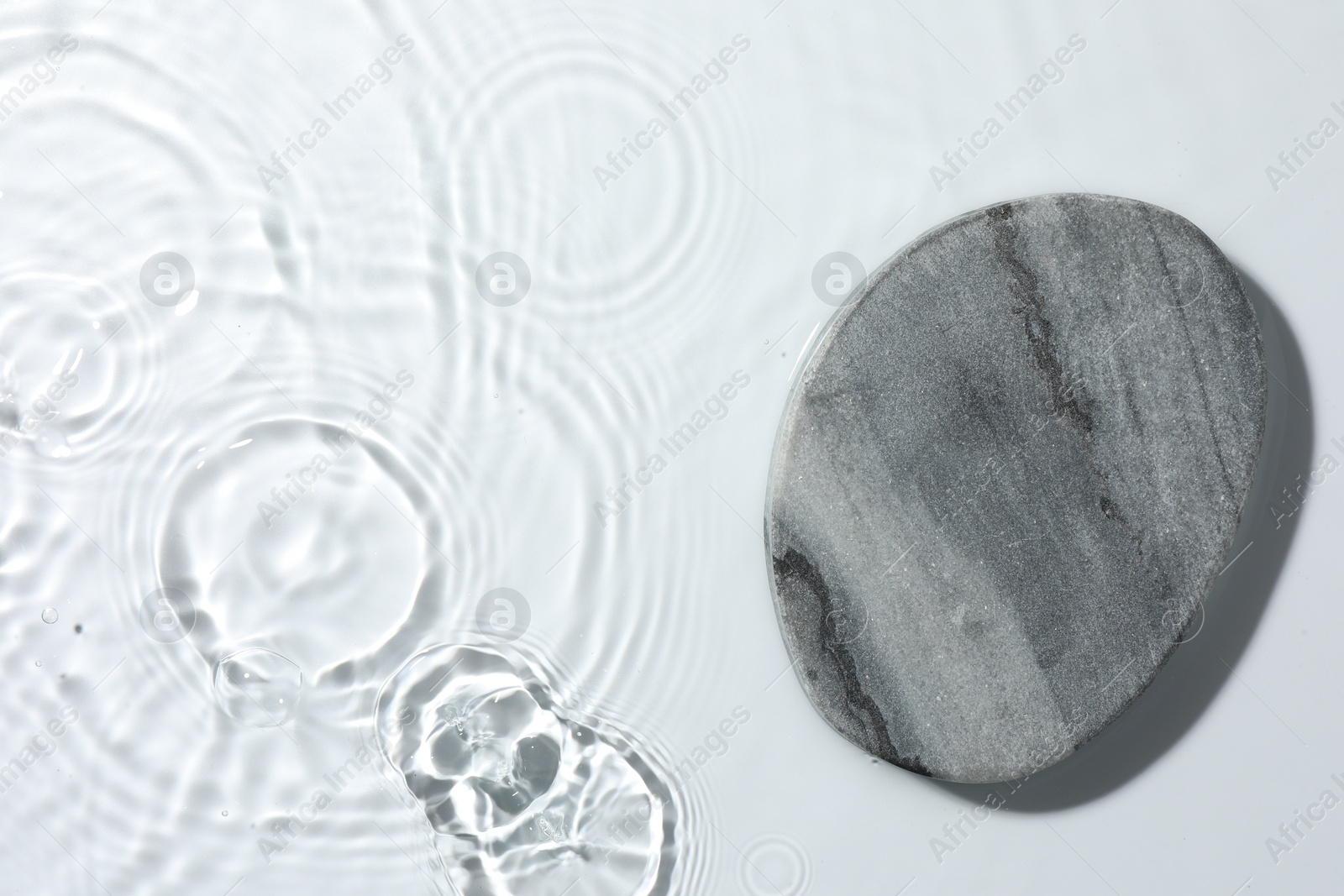 Photo of Presentation of product. Stone podium in water on white background, top view. Space for text